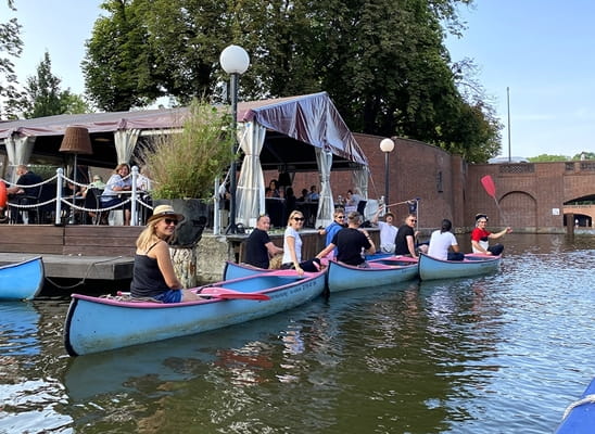 Canvas Reply team canoeing on a city canal during a team event